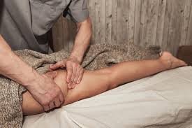 download (8) pessoa deitada na cama massageando as pernas, com luz suave e ambiente relaxante.