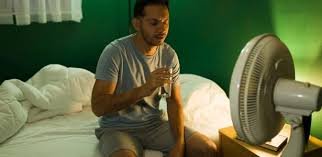 images (2) Pessoa com sudorese noturna sentada na cama durante a madrugada.