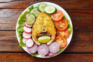 Prato de dieta cetogênica ou paleo peixe grelhado e legumes na mesa de madeira rústica Comida com baixo teor de carboidratos alimentação saudável vista superior prato leve com legumes e peixe grelhado sobre mesa posta para o jantar