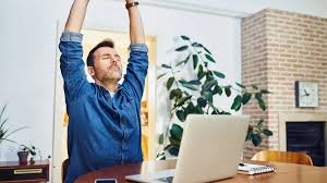 download (60) Pessoa em home office fazendo alongamento ao lado da mesa.