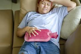 download (13) mulher com TPM sentada no sofá segurando bolsa térmica