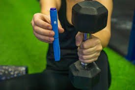 download (27) Pessoa treinando musculação segurando halteres ao lado de caneta emagrecedora