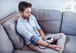 images (2) Pessoa medindo pressão arterial em casa com aparelho digital de braço