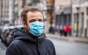 download (17) pessoa com máscara cobrindo boca e nariz em ambiente urbano