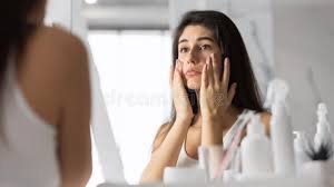 download (11) mulher observando pele opaca diante do espelho