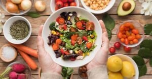 images Fotografia realista e horizontal mostrando uma alimentação equilibrada sobre uma mesa clara, com frutas, verduras, legumes, grãos integrais e um copo de água. A composição deve transmitir saúde intestinal e prevenção, sem desenhos anatômicos exagerados.